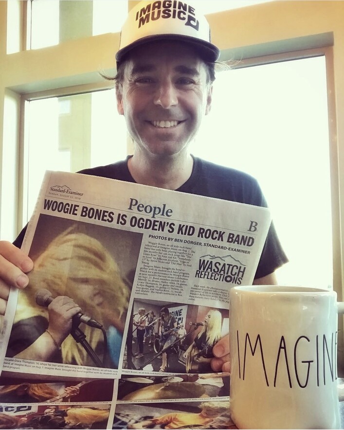 Imagine Music founder David Owen holding the Standard-Examiner story about an Imagine Music kid rock band